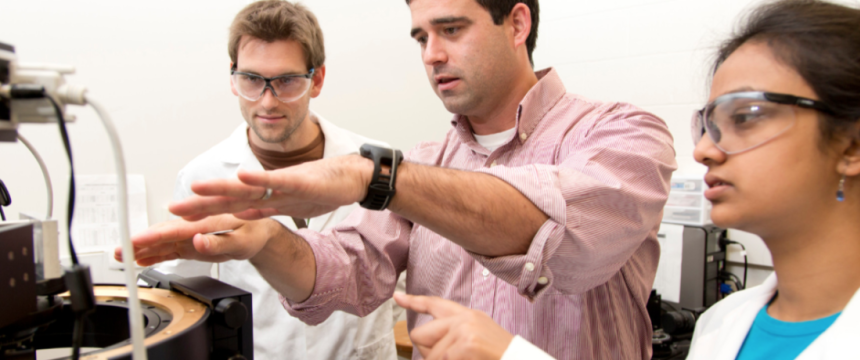 Faculty and Chemistry Graduate Students working in Laboratory|Chemistry Ph.D. student Evan White, left to right, talks with professor Jason Locklin and fellow Chemistry Ph.D. student Anandi Roy about an experiment on a m...