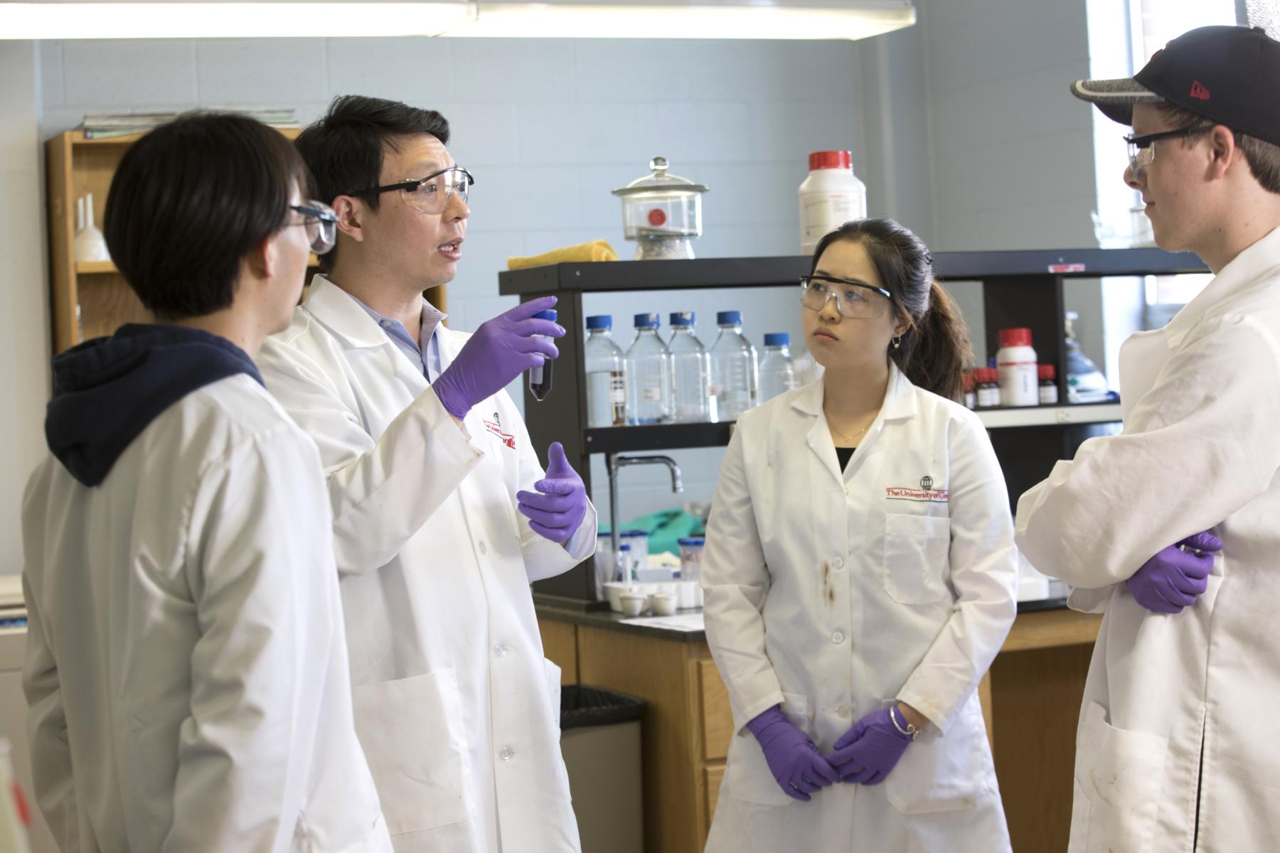 Students listening as professor demonstrates lab technique