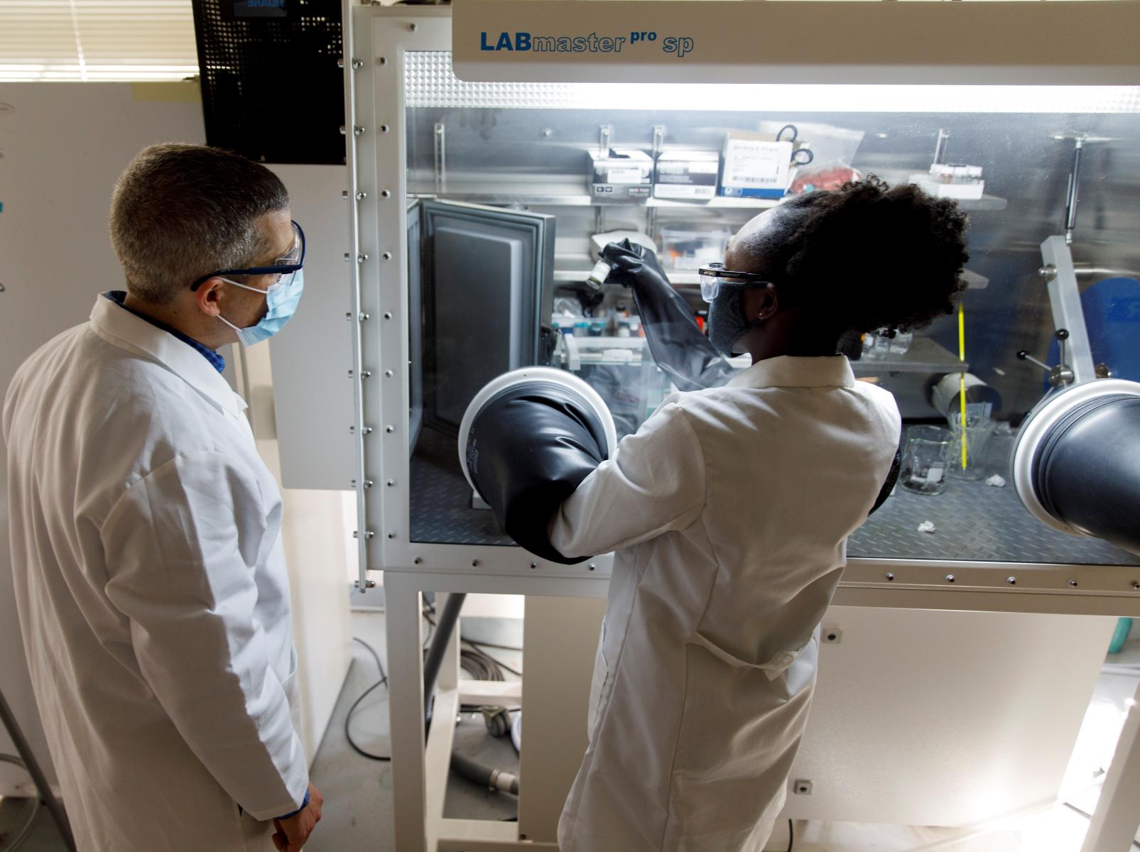 Man and woman observing experiment results in glove box