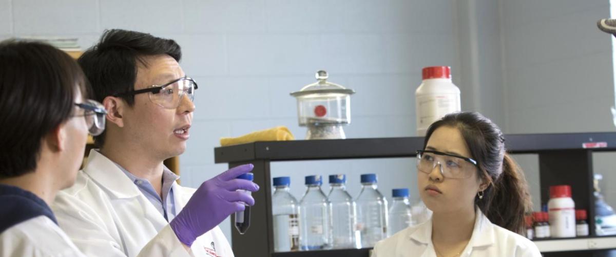 Students listening as professor demonstrates lab technique