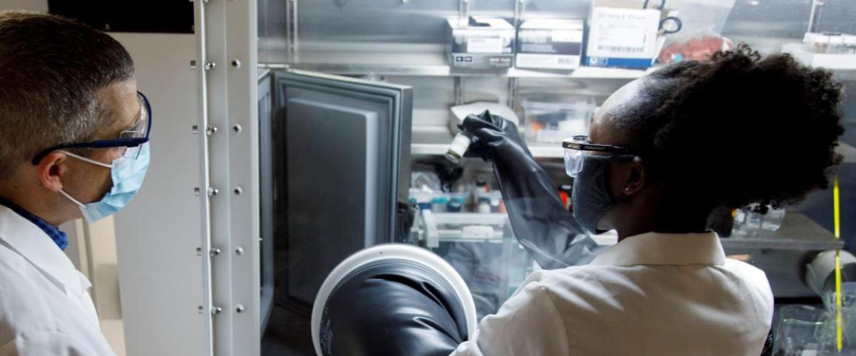 Man and woman observing experiment results in glove box