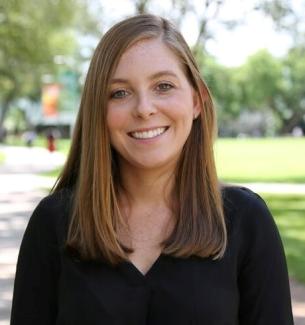 Head shot of Prof. Katlyn Meier, woman with long brown hair and a black sweater, outdoor background