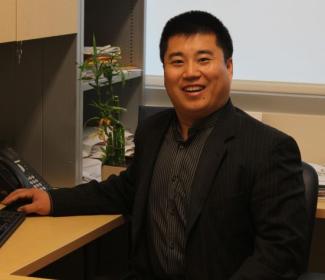 Photo of Dr. Chengshan Wang, speaker, seated at his desk